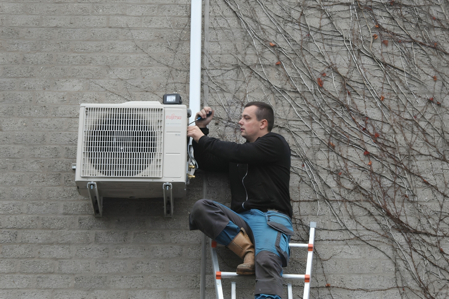 Ruben de wit op ladder een airco aan het onderhouden